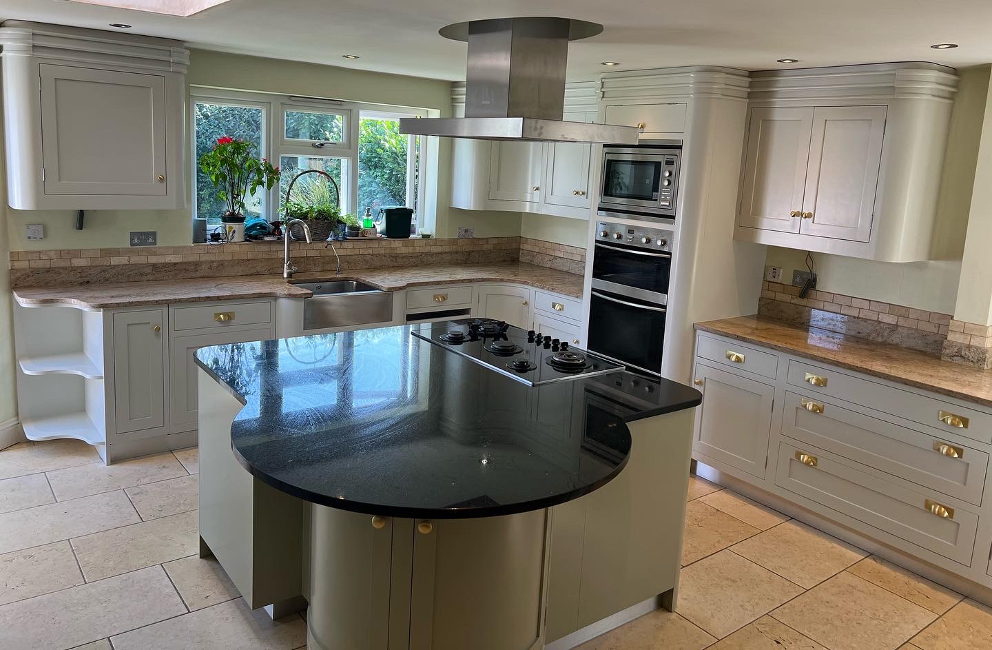 Hand-painted cream shaker kitchen with a green central island, oak worktops and bespoke fitted cabinetry.