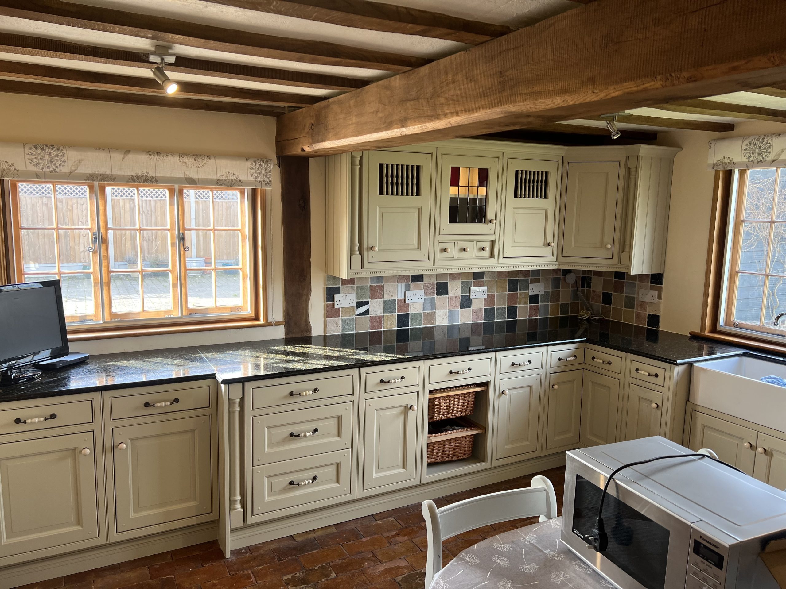 Hand-painted cream shaker kitchen with solid wood worktops, exposed ceiling beams and traditional fitted cabinetry.
