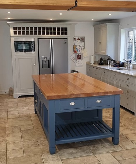 Hand-painted blue kitchen island with a solid oak worktop, traditional shaker cabinetry and chrome cup handles.