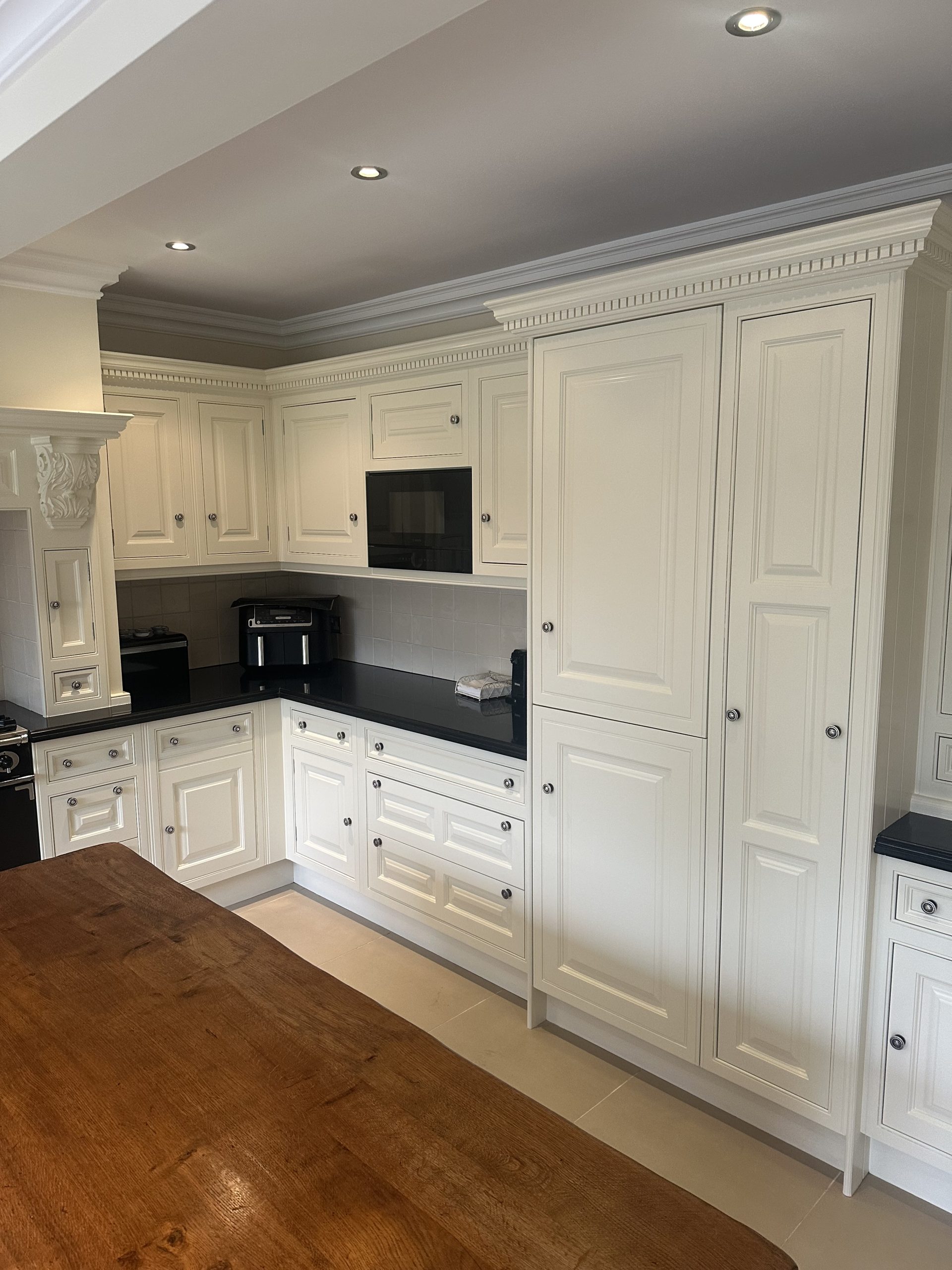 Hand-painted white kitchen with black worktops, traditional shaker cabinets and integrated appliances.