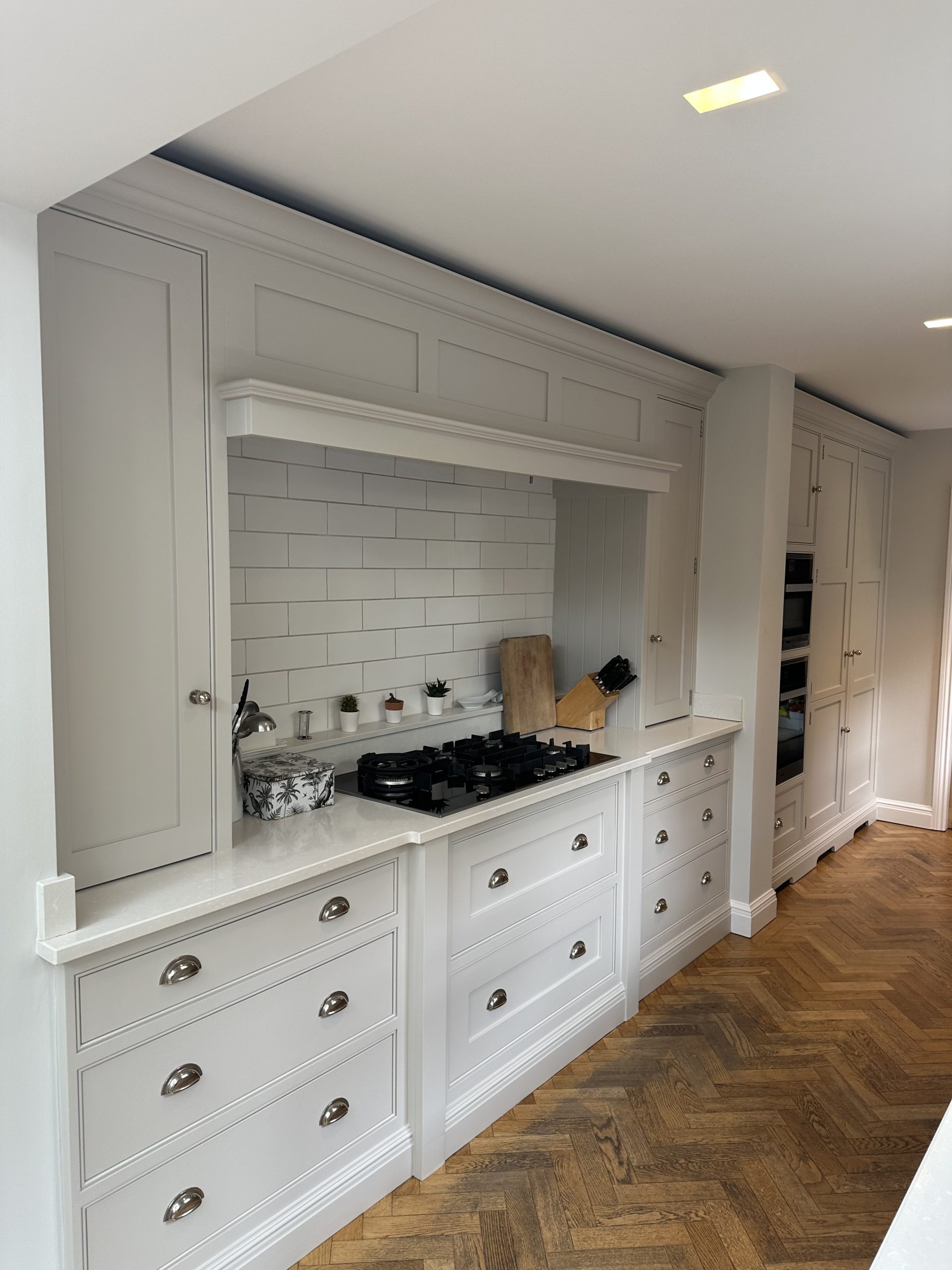 Hand-painted white shaker kitchen with subway tile splashback, bespoke cabinetry and stone worktops.