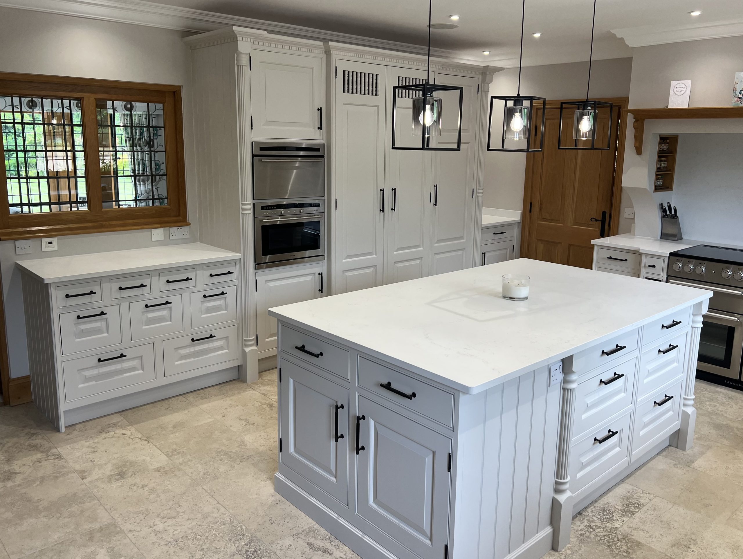 Hand-painted white shaker kitchen with a central island, stone worktops and bespoke fitted cabinetry.